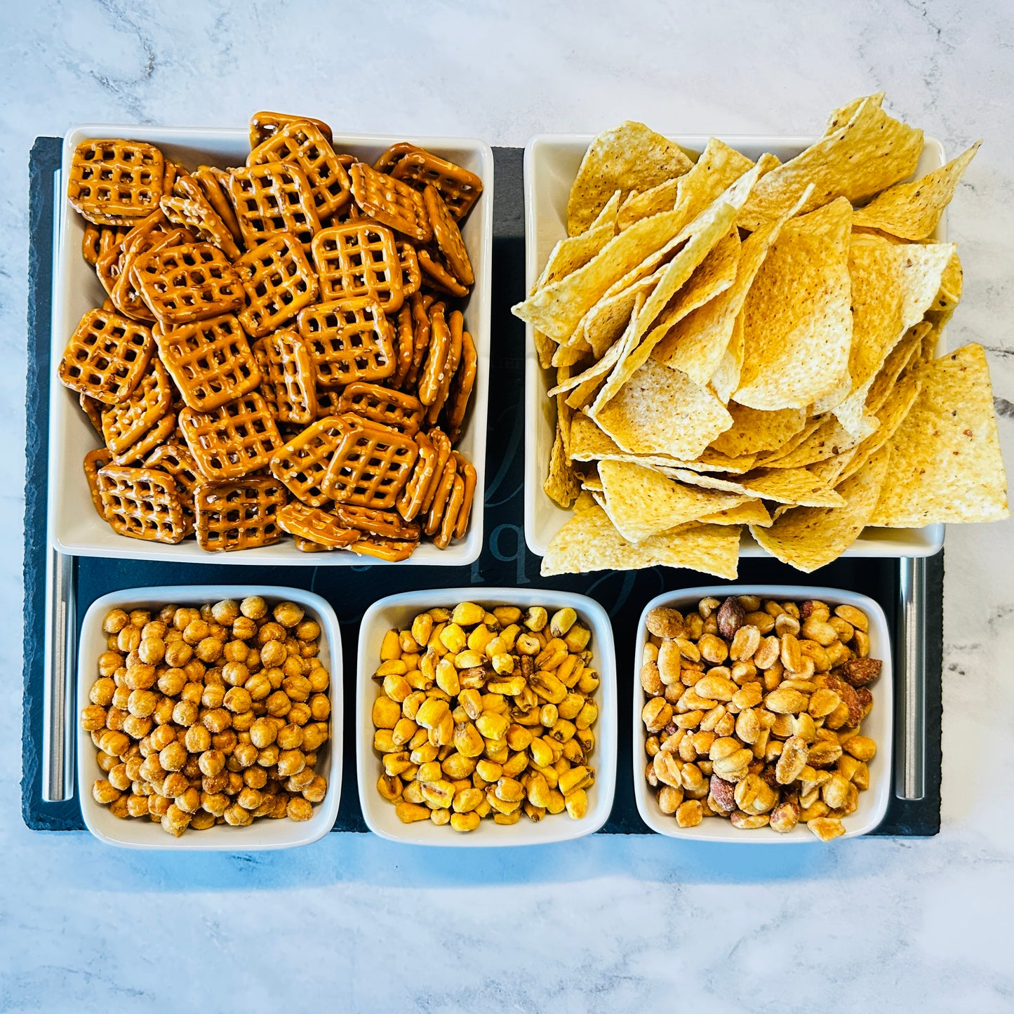 Large Tray with large bowls of chips and pretzels and 3 small bowls with snacks